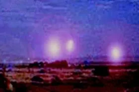 Glowing balls of light hovering over dark scrubland at night