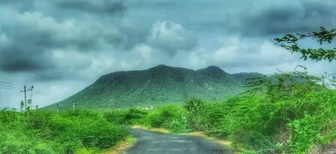 Dhinodhar Hill covered in green during the monsoon, with a road in the foreground