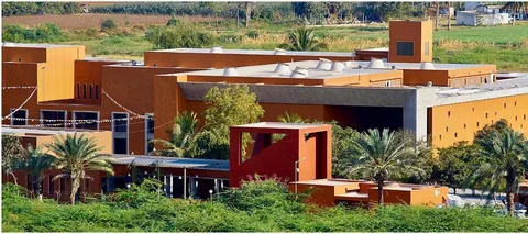 Ochre buildings of the Living and Learning Design Centre among palm trees