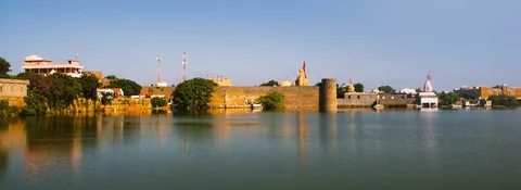 Narayan Sarovar lake with the old fort wall and temple spires reflected in the water