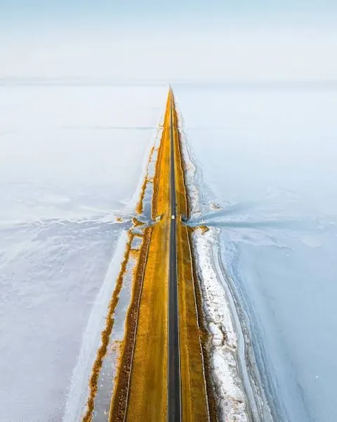 Aerial view of a straight road running across the white salt of the Rann