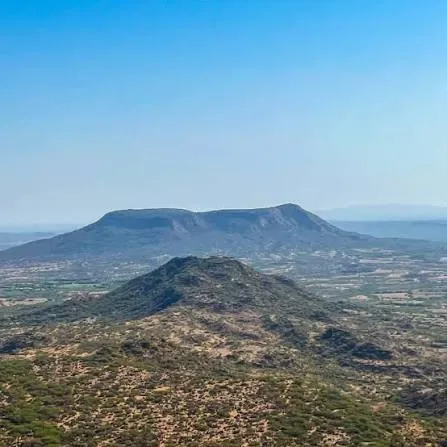 Flat-topped hill rising behind a smaller conical hill in the dry season