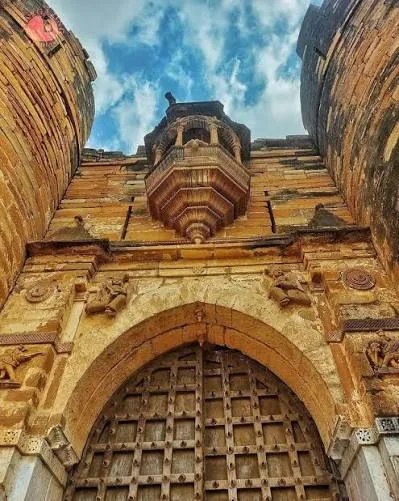 Carved stone gateway with an overhanging balcony at Tera Darbargadh