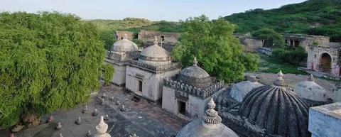 Domed samadhis and old monastery buildings at Than, with green hills behind